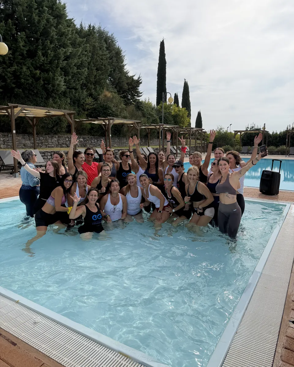 Le partecipanti di Escape 2026 in piscina con le braccia alzate